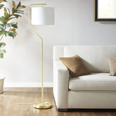 Angular arched metal floor lamp with gold finish and white drum shade beside beige sofa in living room