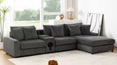 Dark gray corduroy sectional sofa with Bluetooth speakers, console with USB charger and cup holders, movable ottoman, and storage compartments in modern living room.