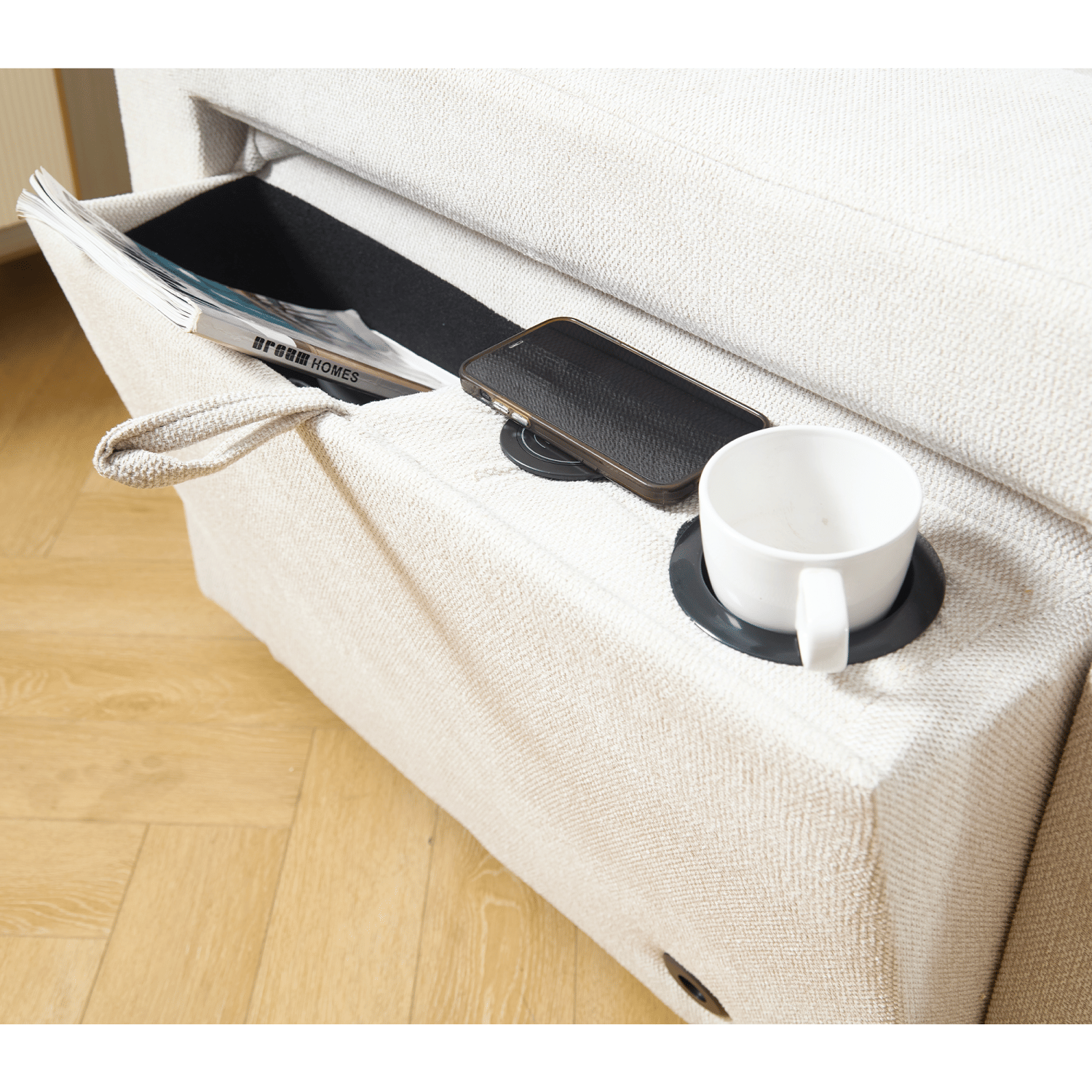 Beige sectional couch armrest with book storage, wireless charging port, and cup holder for living room.