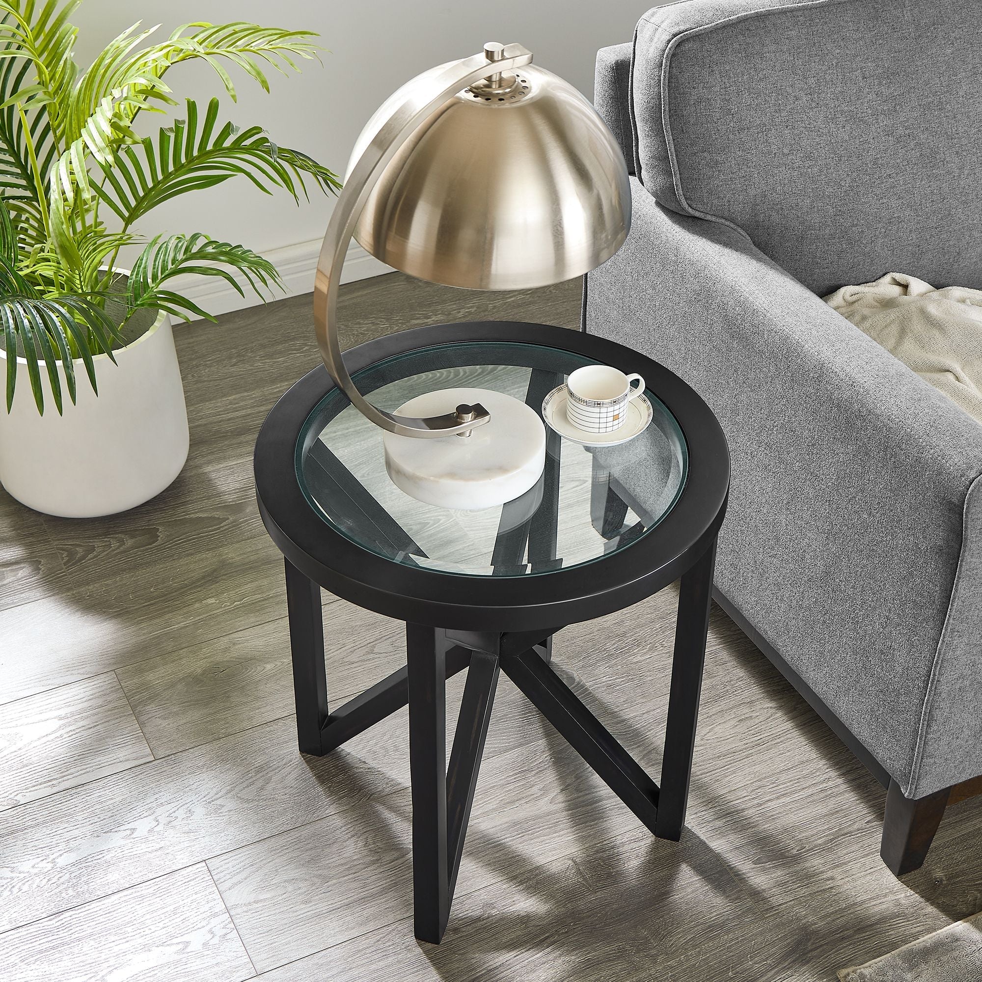 modern simple glass round coffee table with black solid wood base and tempered glass top in living room setting