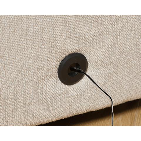 Beige soft linen fabric sectional couch close-up showing built-in wireless charging port on the side panel.