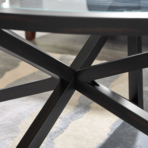 Close-up of modern simple glass coffee table with black solid wood base and round tempered glass top