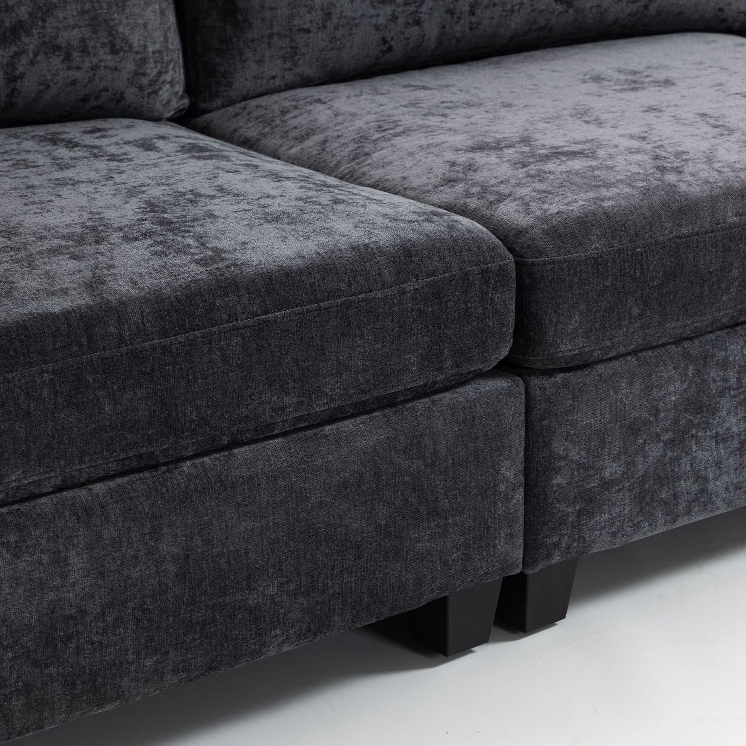Close-up of ultra-soft XXXL dark grey chenille 3-seater sofa with plush cushions and black legs