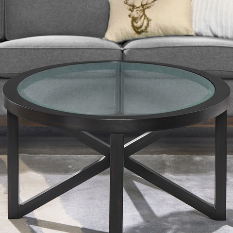 Round modern simple glass coffee table with black solid wood base and clear tempered glass top in living room setting